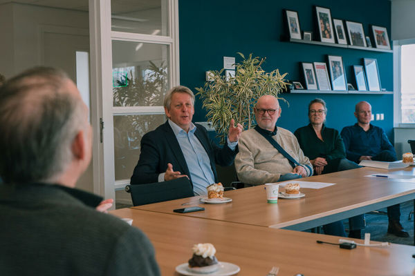 Meerdere mannen zitten aan tafel in een vergaderruimte
