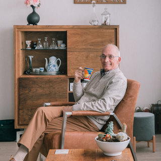 Oudere man drinkt een kop koffie in de stoel