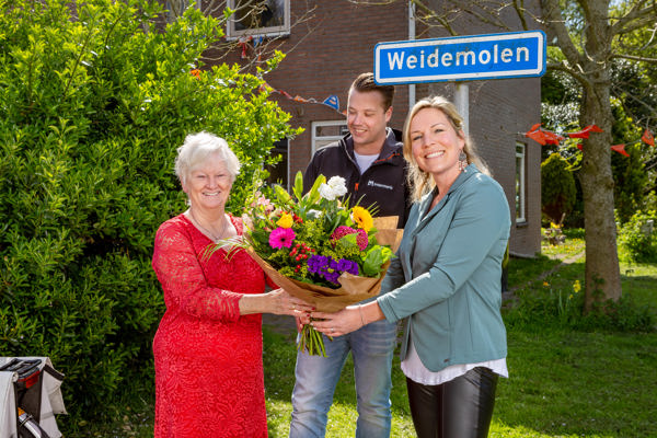 Bewoner ontvangt een bos bloemen van twee medewerkers van Intermaris