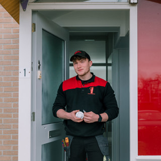 Man staat met een rookmelder in zijn hand in de deuropening