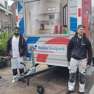 Drie schilders staan bij een bouwkeet