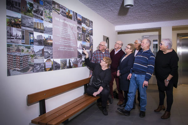 Bewoners kijken naar fotocollage aan de muur