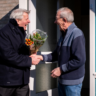 Bewoner ontvangt een bos tulpen van de directeur tijdens complimentendag