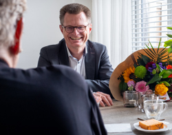 Directeur Cees Tip zit aan tafel waar een bos bloemen op ligt