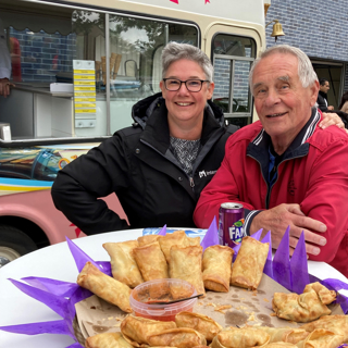 Een man en een vrouw staan bij een schaal met hapjes