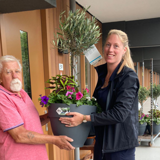 Bewoner ontvangt een boompje in een pot van een medewerker van Intermaris