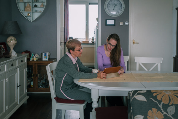 Twee bewoners kijken samen aan tafel op een tablet