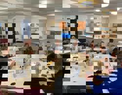 Diverse mensen zitten om tafel met papieren op tafel