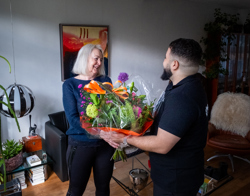Bewoonster ontvangt uit handen van medewerker Intermaris een bos bloemen