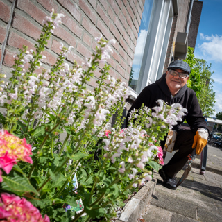 Bewoner poseert bij kleurrijk geveltuintje
