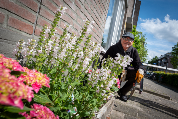 Bewoner poseert bij kleurrijk geveltuintje