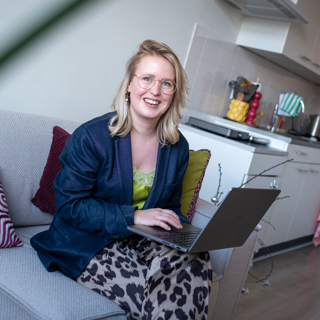 Bewoonster in haar woning op de bank met laptop