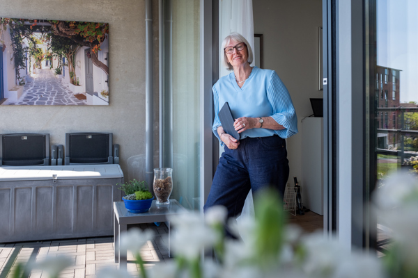 Mevrouw Van der Weide poseert met iPad in hand op haar balkon