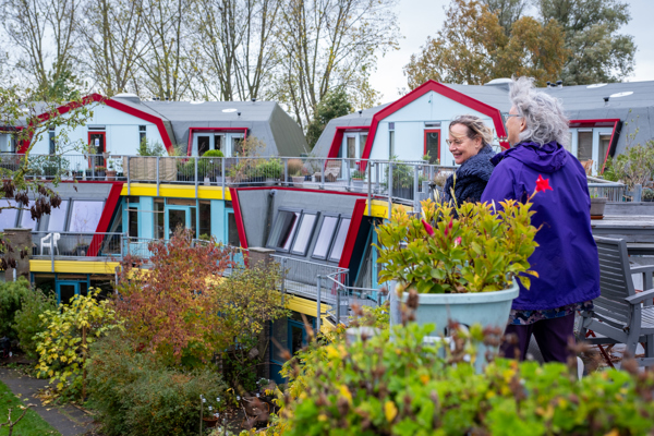 Twee bewoonsters staan op een balkon met plantenbakken