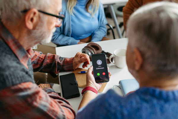 Personen zitten aan tafel met mobiele telefoon in de hand