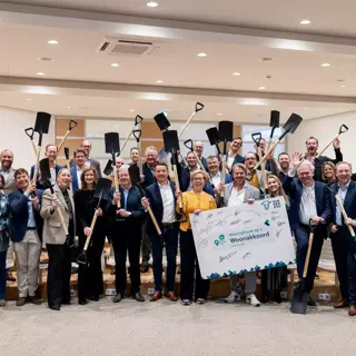 Diverse mensen staan op een groepsfoto met een sneeuwschuiver in de hand