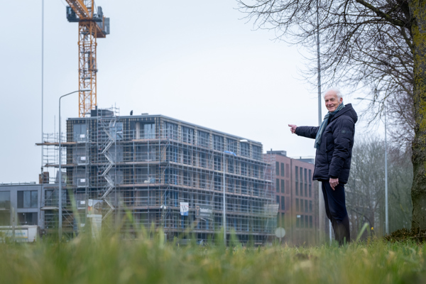 Bewoner staat buiten voor woongebouw dat nog gebouwd wordt