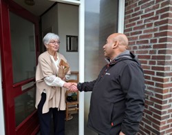 Wijkcoach overhandigt tulpen aan huurder