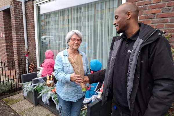 Wijkconsulent geeft tulpen aan huurder